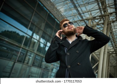 Urban Business Man In Sunglasses Talking Smart Phone Traveling Walking Outside Airport. Casual Young Businessman Wearing Suit Jacket. Handsome Male Model In 20s, Manager, City Hall, Cell.