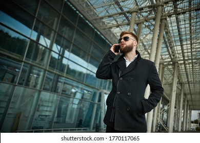 Urban Business Man In Sunglasses Talking Smart Phone Traveling Walking Outside Airport. Casual Young Businessman Wearing Suit Jacket. Handsome Male Model In 20s, Manager, City Hall, Cell.