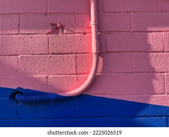 Urban cable plastic flexible conduit painted pink on funky wall background 