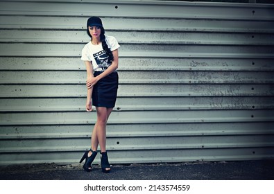 Urban chic. Portrait of a stylishly dressed young woman standing in front of a metal wall.