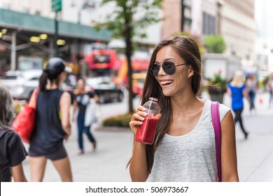 Urban city lifestyle hipster asian woman drinking healthy fruit vegetable berry juice smoothie walking on downtown street of New York city, NYC, USA. Happy young adult health diet concept.