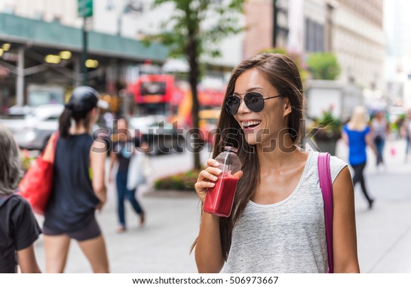 Urban\
city lifestyle hipster asian woman drinking healthy fruit vegetable\
berry juice smoothie walking on downtown street of New York city,\
NYC, USA. Happy young adult health diet\
concept.