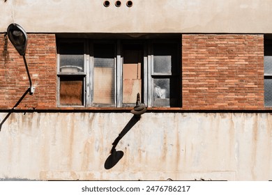 Urban Decay: Uneven Windows and a Lonely Lamp on a Weathered Brick Wall. The stark contrast between architectural abandonment and the resilience of time in an urban setting - Powered by Shutterstock