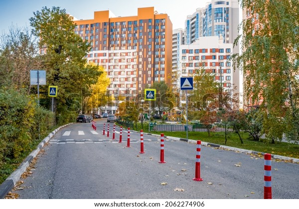Urban development road pedestrian cross\
with Traffic barriers as poles, and speed\
dump