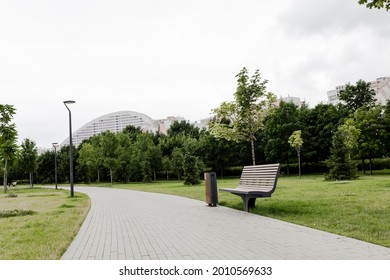 Urban Environment. Efficient Modern City. City ​​park In Summer On A Cloudy Day. Empty Bench And Tile Path