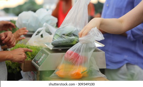 Urban Green Market Series/buyer Collecting Plastic Bag Of Produce With Scale In The Background