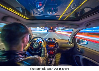 Urban high spees driving on a smal city car with panoramic roof. View from inside car natural light street and other cars is motion blurred.