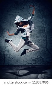 urban hip hop dancer with grunge concrete wall background texture jumping and dancing with hoodie