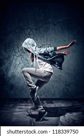 urban hip hop dancer with grunge concrete wall background texture jumping and dancing with hoodie