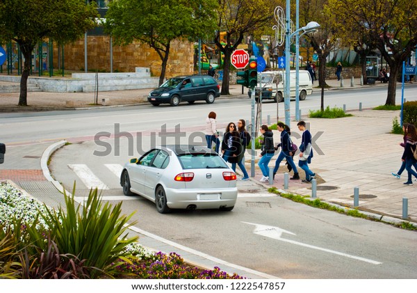Urban image of the\
city road and group of young people walking and crossing the road\
at zebra crossing. Greek street background at Thessaloniki Greece\
in March 2018.