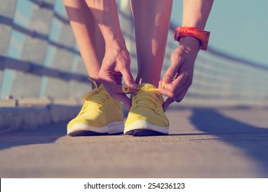 Urban jogger tying his running shoes on a big bridge. - Powered by Shutterstock