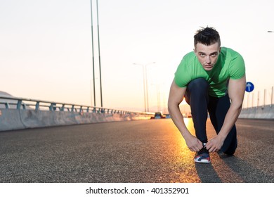 Urban jogger tying his running shoes on a big bridge. sunset highway - Powered by Shutterstock