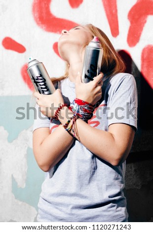 Urban lady with bracelets and bandana on hands with crosser arms raising head with graffiti wall on background