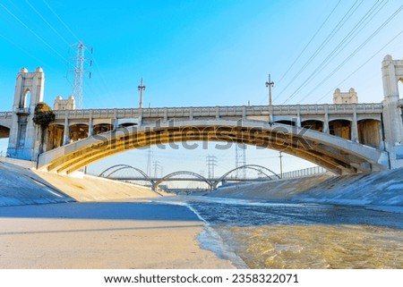 Urban landscape featuring the LA River, its connecting bridges and the intricate lattice of powerlines.
