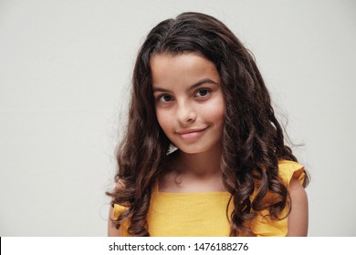urban lifestyle portrait of a confident and gorgeous mixed race child face, multiethnic tween preteen teen girl with beautiful curly hair wearing yellow summer dress, smiling at camera, youth day