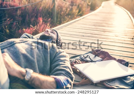urban man lying on a catwalk in the field enjoying nature