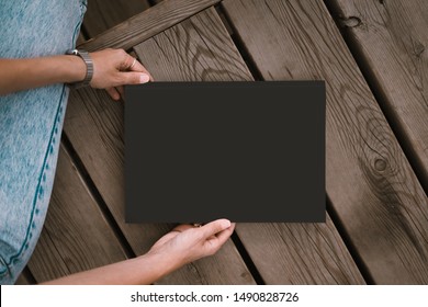 Urban mockup of paper folder. Girl holding black paper folder. Template can be used for you design 
