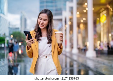 Urban modern lifestyle fashion portrait of asian young female stylish casual Asia woman walking 
with coffee cup and smartphone connection on the street, wearing cute trendy outfit after raining - Shutterstock ID 2174138963