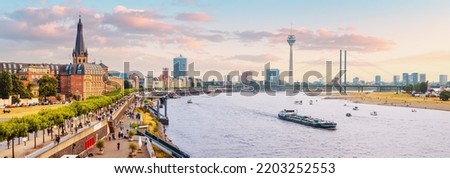 Urban panoramic cityscape view of Dusseldorf old town and transportation waterway of the whole of Germany - the Rhine River, along which large barges and small ships are sailing
