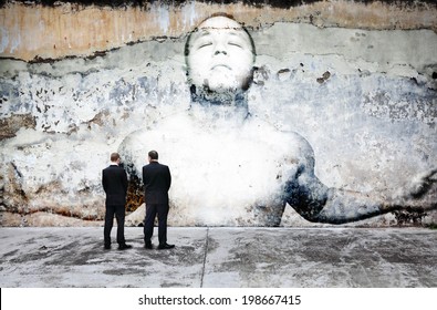 Urban people looking at a dilapidated paintwork of a peaceful meditating man on a weathered concrete wall for the concept of urban concrete stress.