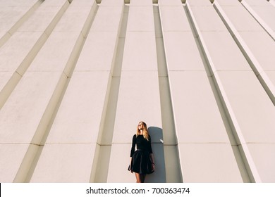 Urban picture of stylish girl near modern wall with vertical lines