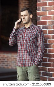 Urban Portrait Of Millennial Handsome Serious Man 30-35 Years Old Talking On Mobile Phone