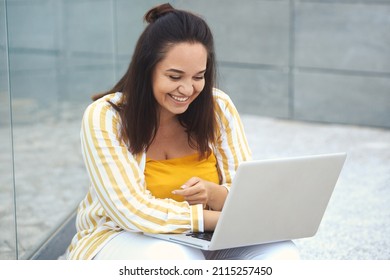 Urban Portrait Of Positive Plus Size Woman 30-35 Years Old In Fashion Clothes Working Remotely On A Laptop On Vacation. Close-up Fat Female Freelancer Typing On A Computer In The Park Outdoors