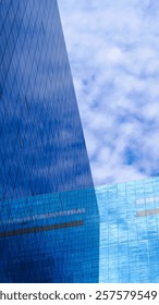 Urban Reflection – Strikingly sharp angles of a glass skyscraper reflecting the dynamic patterns of clouds, illustrating the harmony between modern architecture and nature