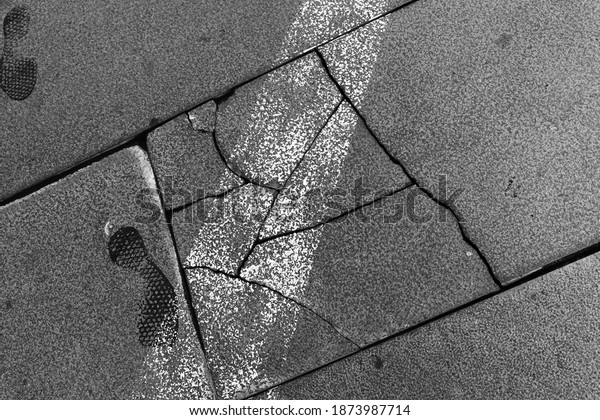 Urban\
road surface with cracks, road marking line and footprint,\
close-up. Transportation background photo\
texture