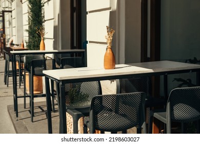 Urban Scene Of A Nice Terrace Of An European Cafe With No People In Sunlight. Black And White Furniture.