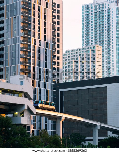 Urban scene with\
people mover rail car above riverside dining and commerce area in\
Miami Florida financial and residential district showing public\
transportation at work