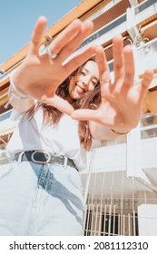 Urban Shot Of A Modeling Young African Woman With Long Hair Smiling And Making Poses To Camera. City Urban Concept. Happy Day On The City, White Shirt Blue Jeans. Modern Outfit Styling. Street Life.