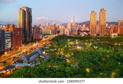 Urban Skyline Of Taipei City At Sunset Viewed From Daan Forest Park, With Residential Buildings Surrounding The Oasis & 101 Tower Standing Out Amid High-rise Office Blocks In Xinyi Commercial District