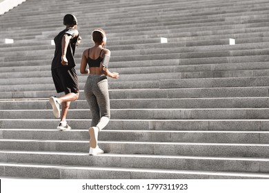 Urban Sport. Fit Black Man And Woman Running Up Steps In City Park, Enjoying Training Outdoors, Rear View With Copy Space