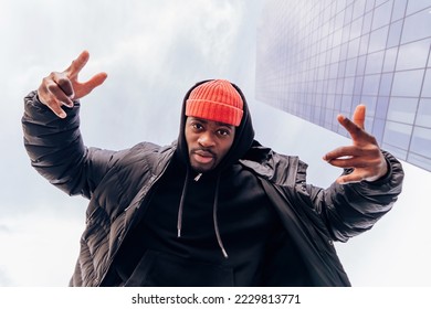 urban street fashion bottom view portrait of a modern african american hip hop cool rapper under skyscraper - Powered by Shutterstock