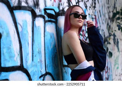 Urban street portrait of a girl with sunglasses and pink hair