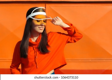 Urban Summer Fashion Girl with Sporty Hoodie and Clear Cap. Fashionable woman in retro colorful décor enjoying sun in summertime
