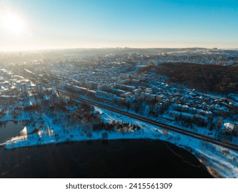 An urban sunrise in winter, with the city awakening to a fresh snowfall. Buildings and streets are blanketed in white as the early morning light reflects off the icy surfaces. 