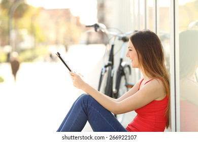 Urban teen girl using a tablet sitting in the street with a bicycle in the background - Powered by Shutterstock