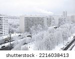 Urban winter landscape. A snow-covered city street, trees covered with snow. View from above. Cloudy winter day, soft light.