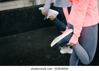 Urban Workout And Running Concept. Women Stretching Legs For Warming Up Before Exercising.