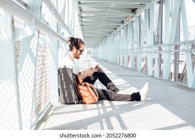 Urban Young Man Talking On Smart Phone Traveling Inside In Airport. Casual Young Businessman Wearing Suit Jacket. Handsome Male Model. Young Man With Cellphone At The Airport While Waiting For