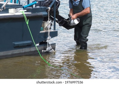 Urgent Boat Repair. The Man Changes The Propeller Of The Outboard Motor Of The Boat.