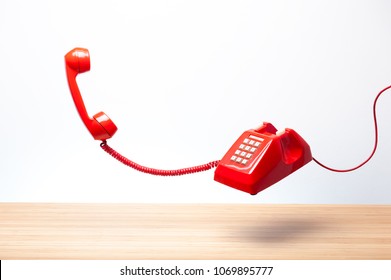 Urgent Call Waiting , Classic Red Telephone Receiver, Old Telephone On White Background, Flying In Weightlessness With Wooden Desktop.