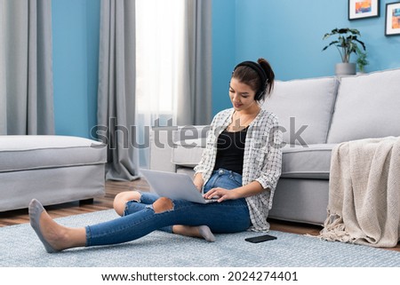 Urgent student sits on floor with laptop and headphones, transcribes notes, studies for exams, tests, reads information, looks up answers to questions, busy, remote school, online teaching