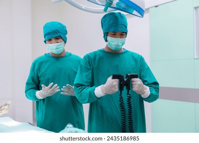 urgeon doctor hand hold defibrillator to pump chest heart patient to save life sick people in operating room at hospital. - Powered by Shutterstock