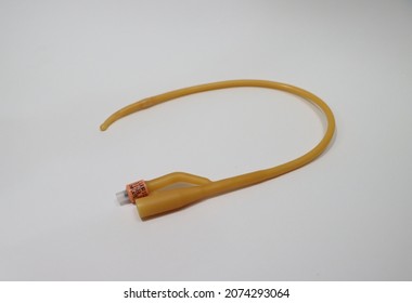 Urinary catheter. Yellow latex Foley catheter. Medical urology equipment that is inserted into the bladder to facilitate the passage of urine. Item is isolated on a white background. Selective focus.