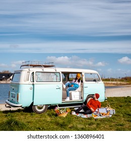 Urk Netherlands April 2019,  couple having a picnic on the beach with an old classic camper van, Classic Minty Green and white VW Camper Van parked on Seafront 
