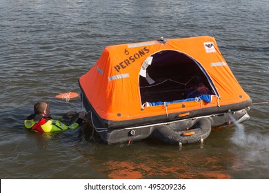 URK, THE NETHERLANDS - SEP 24: Rescue worker showing how to use a life raft on September 24, 2016 in the harbor of Urk, the Netherlands