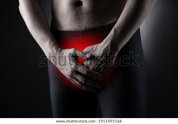 Urological genital infections concept, pain in\
prostate, man suffering from prostatitis or from a venereal disease\
on black background